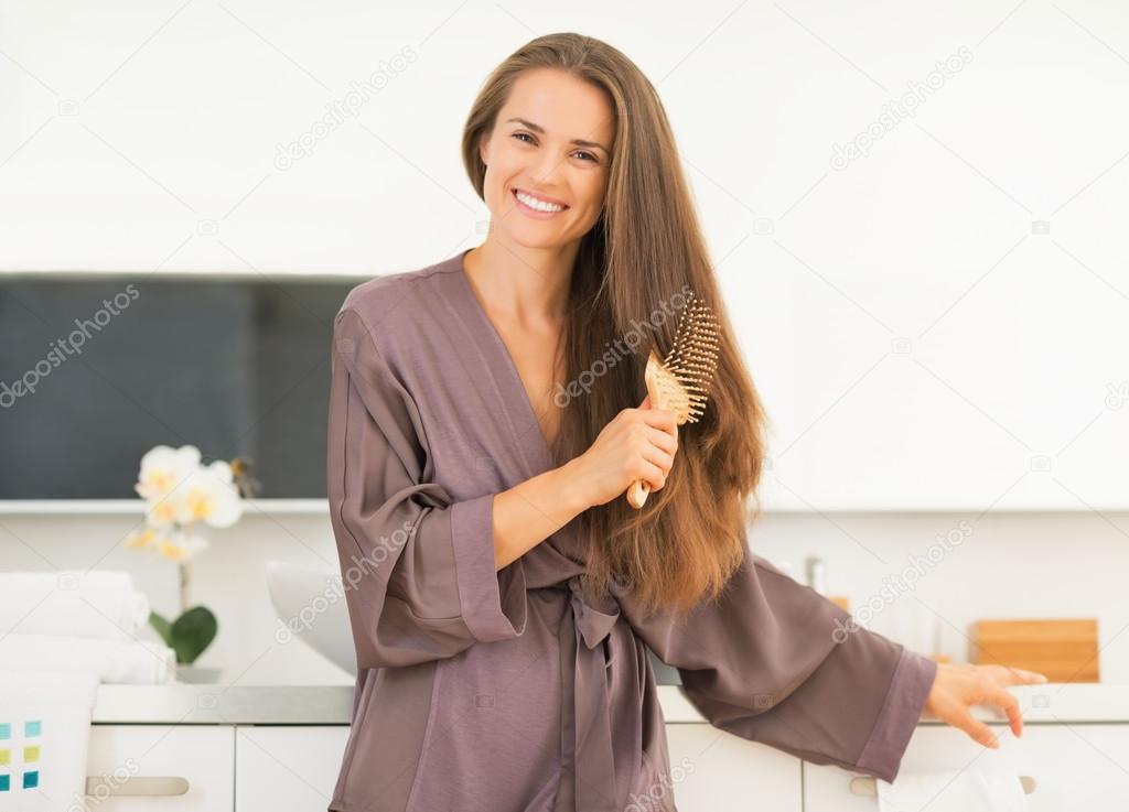 Woman combing hair in bathroom