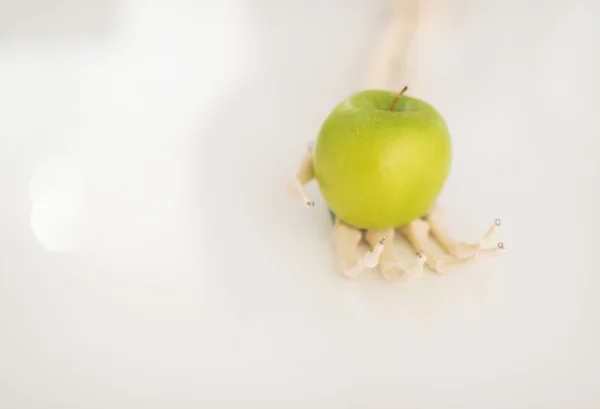 Skeleton hand holding apple — Stock Photo, Image