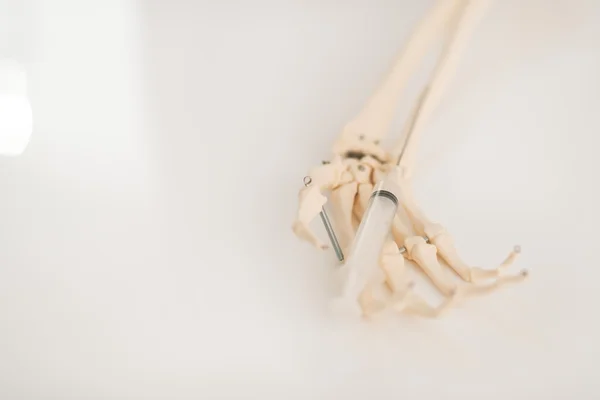 Human skeleton hand holding syringe — Stock Photo, Image