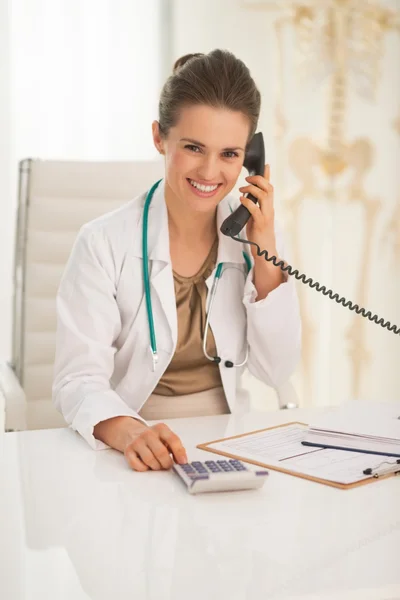 Doctor with calculator talking phone — Stock Photo, Image