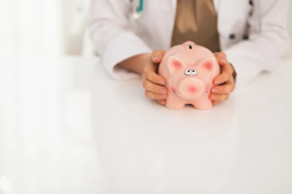 Medical doctor holding piggy bank — Stock Photo, Image
