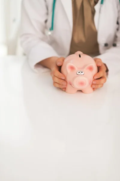 Medical doctor showing piggy bank — Stock Photo, Image