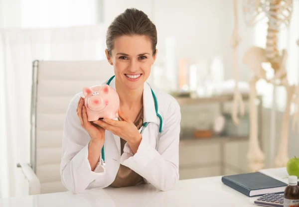 Médico mulher mostrando banco porquinho — Fotografia de Stock