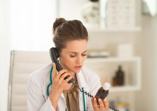 Γιατρός με φιάλη φαρμάκου μιλάμε τηλέφωνο — Φωτογραφία Αρχείου