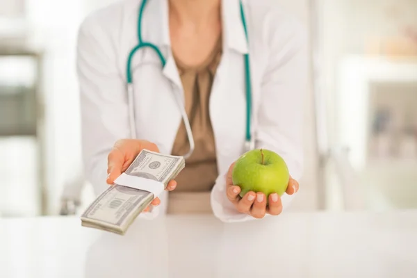 Doctor holding apple and money pack — Stock Photo, Image