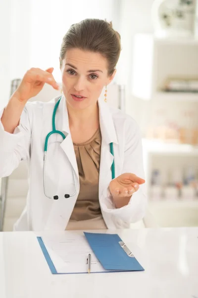 Doctor woman sitting in office and explaining — Stock Photo, Image