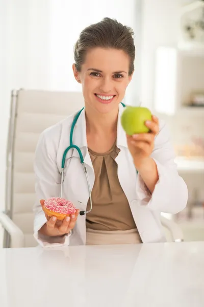 Doctor woman giving apple instead of donut — Stock Photo, Image