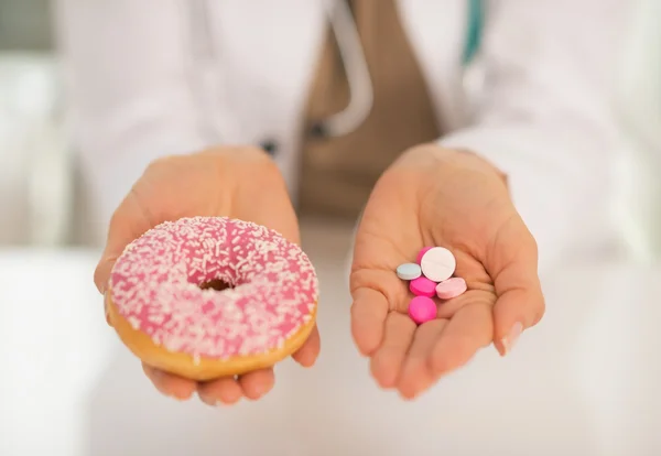 Medico donna mostrando ciambella e pillole — Foto Stock