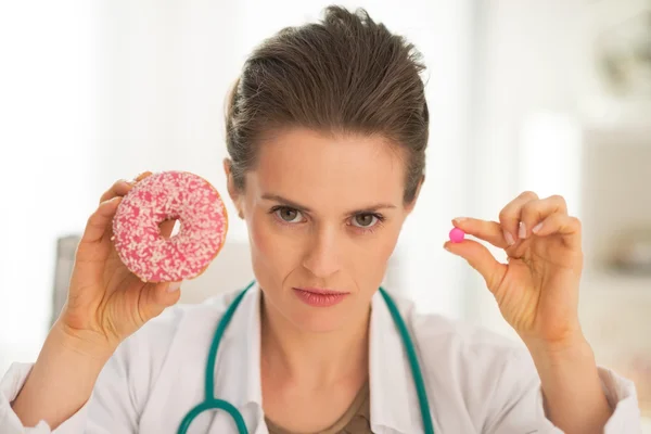 Doctor woman showing donut and pill — Stock Photo, Image