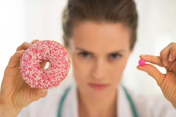 Médico mulher mostrando donut e pílula — Fotografia de Stock