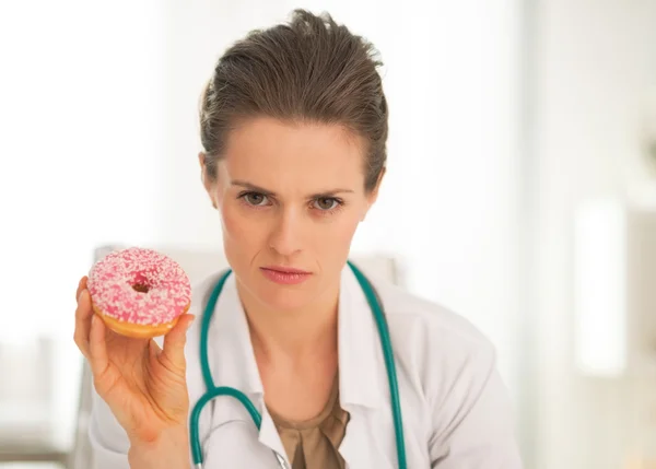 Médico sério mostrando donut — Fotografia de Stock