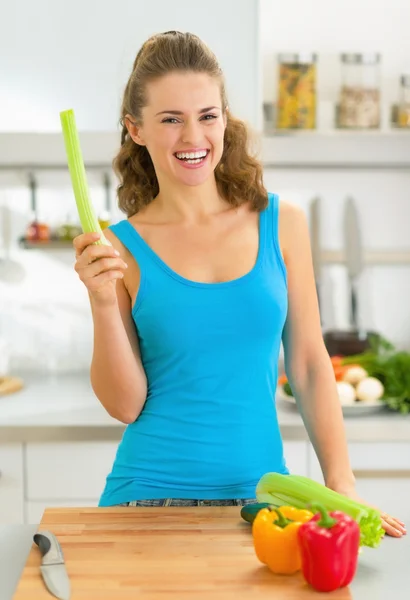 Mujer joven con apio fresco en la cocina — Foto de Stock