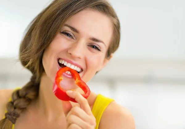 Vrouw eten van paprika in keuken — Stockfoto