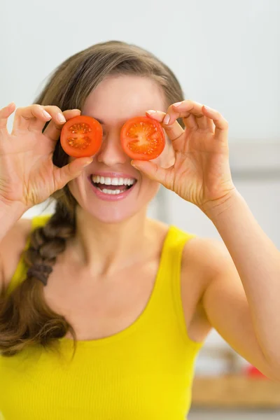 Mulher segurando fatias de tomate na frente dos olhos — Fotografia de Stock