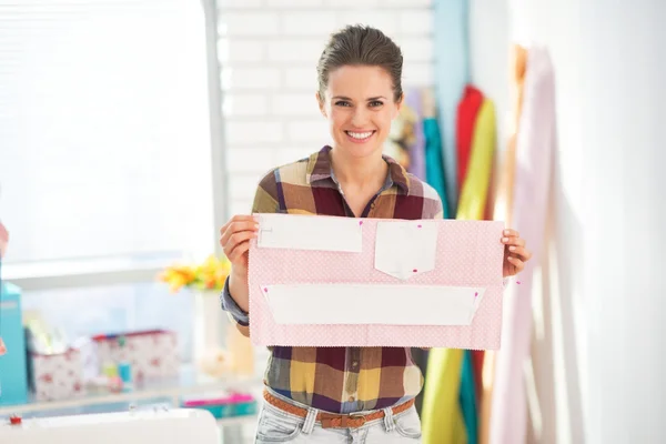 Happy seamstress showing pattern in studio — Stock Photo, Image