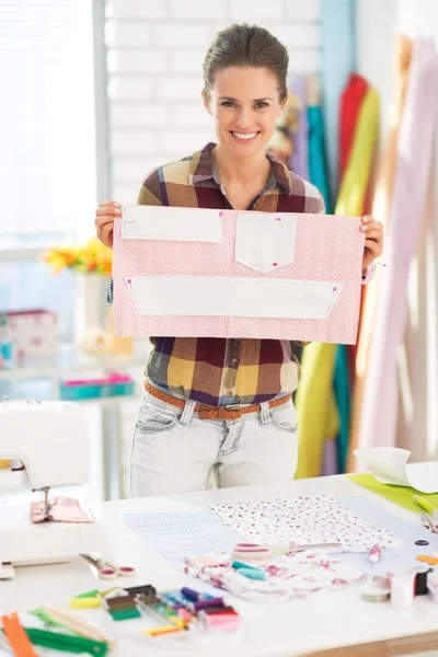 Happy seamstress showing pattern in studio — Stock Photo, Image