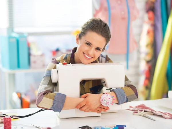 Happy seamstress embracing sewing machine — Stock Photo, Image