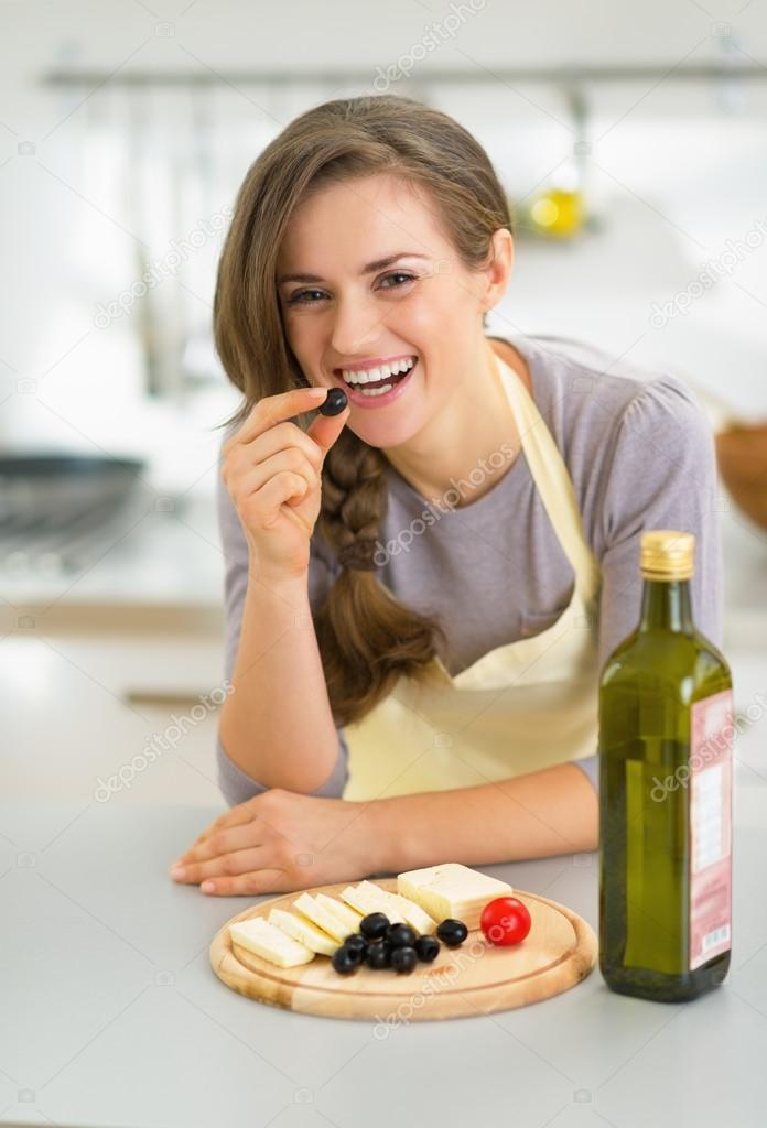Happy housewife eating cheese with olives
