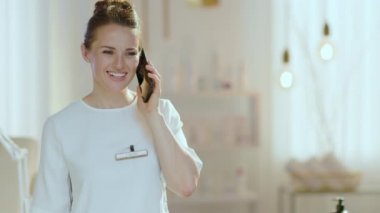 Modern güzellik stüdyosunda akıllı telefondan konuşan 40 yaşında bir kadın çalışan..