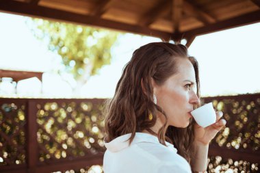 Pansiyon otelinin avlusunda beyaz gömlekli, düşünceli, orta yaşlı bir kadın..