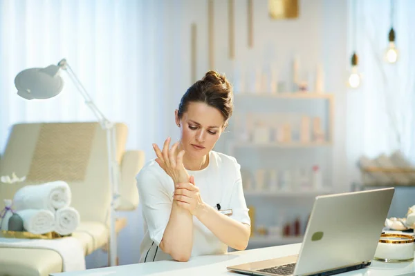 Moe Vrouw Werknemer Met Laptop Met Pols Pijn Moderne Schoonheidssalon — Stockfoto