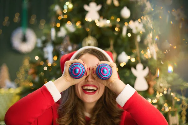 Kersttijd Glimlachende Trendy Huisvrouw Met Kerstmuts Met Behulp Van Kerstballen — Stockfoto