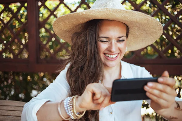 Happy Stylish Woman White Shirt Hat Sitting Table Using Smartphone — Fotografia de Stock