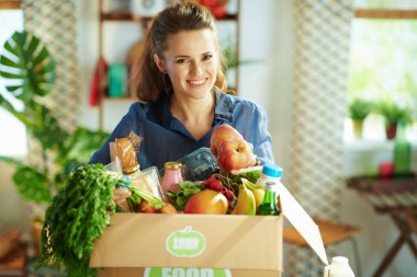 Food delivery. smiling modern middle aged woman with food box in the kitchen.