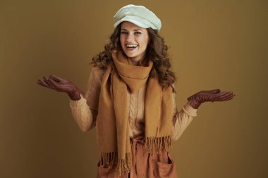 Merhaba Ekim. Mutlu, orta yaşlı, süveterli, deri eldivenli ev hanımı içi boş bir avuç içinde bronz arka planda bir şey sunuyor..