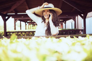 Beyaz tişörtlü mutlu bir kadın çiftlikte akıllı telefondan konuşuyor..