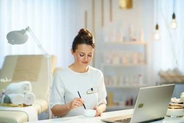 female worker with laptop working in modern beauty studio.
