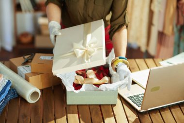 Ofisteki küçük işletme sahibi kadına yakın çekim. Teslimat için ürün paketliyor..