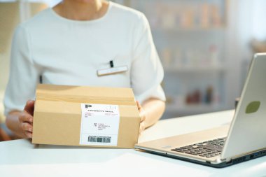 Modern güzellik stüdyosunda dizüstü bilgisayarı ve paketi olan kadın işçiye yakın çekim..