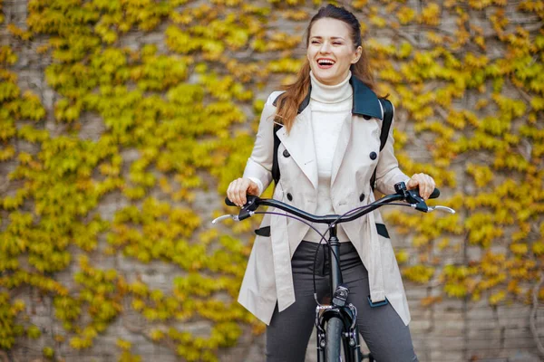 Улыбающаяся Элегантная Женщина Средних Лет Бежевом Плаще Велосипедом Зеленой Стены — стоковое фото