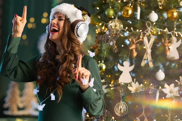 Рождество Счастливая Стильная Женщина Шляпе Санта Клауса Зеленом Платье Слушает — стоковое фото