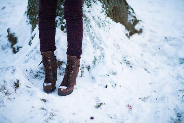 Closeup on female with ankle boots outdoors in the city park in winter.