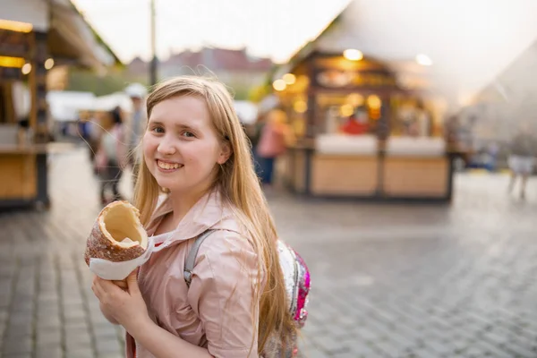 Uśmiechnięta Nowoczesna Dziewczyna Targach Mieście Jedząc Trdelnik — Zdjęcie stockowe