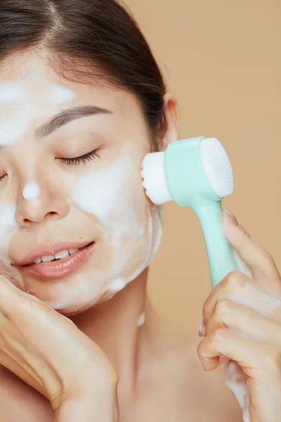 Relaxed Young Asian Woman Massager Washing Face Beige Background — Stock fotografie