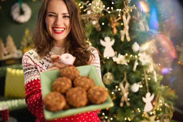 Noel zamanı. Modern evdeki Noel ağacının yanında geleneksel Noel süveteri giymiş, güler yüzlü modaya uygun bir kadın..