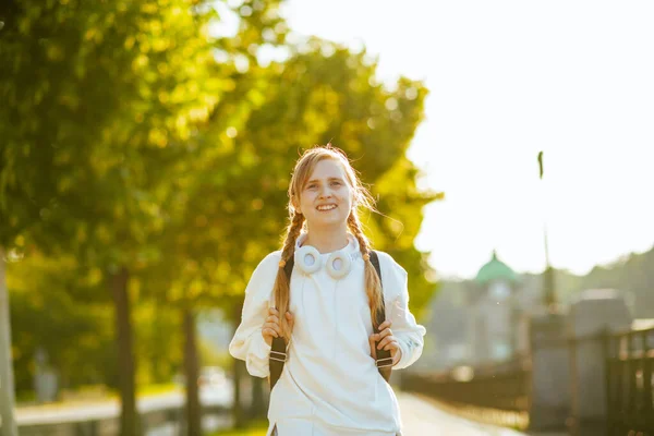 Uśmiechnięta Stylowa Uczennica Białej Bluzie Plecakiem Słuchawkami Chodząca Szkoły Świeżym — Zdjęcie stockowe