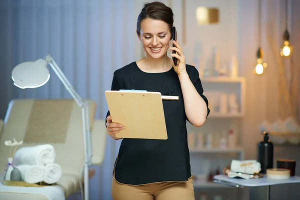 Smiling Female Worker Clipboard Speaking Smartphone Modern Beauty Studio — Stock Photo, Image
