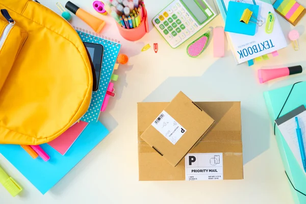 Back to school. Upper view of white table with workbooks, stationary, textbook, parcels and backpack at school child room in sunny day.