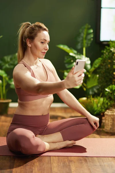 modern woman taking selfie with smartphone in the modern green house.