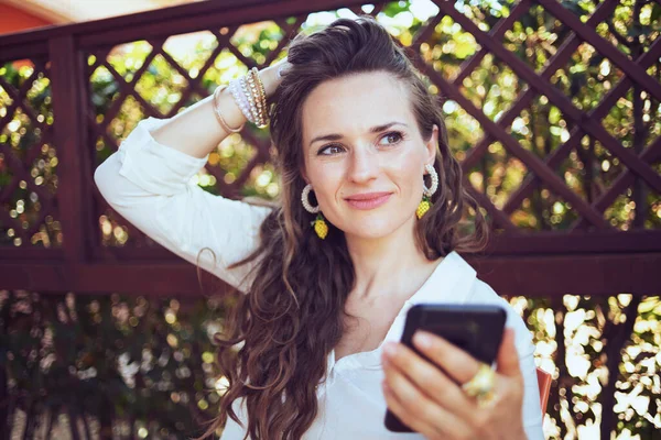 Задумчивая Женщина Средних Лет Белой Рубашке Отправляет Смс Помощью Смартфона — стоковое фото