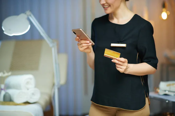 スマートフォンやクレジットカードで笑顔の女性労働者の閉鎖 オンラインショップで現代的な美容室 — ストック写真