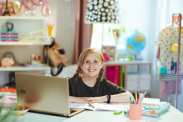 幸せな現代の女の子で灰色のシャツとノートパソコンとワークブックを持っています晴れた日に自宅でオンライン教育 — ストック写真