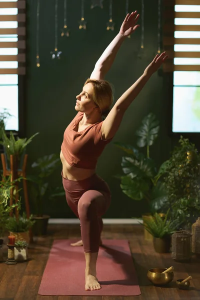 modern 30 years old housewife with yoga mat doing yoga at modern green home.