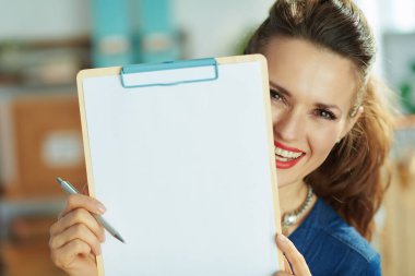 smiling modern small business owner woman with clipboard in the office.