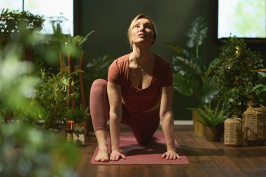 Modern yeşil evde yoga minderi esneyen modern kadın..