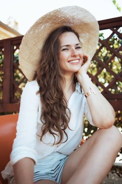 Verandada şapkalı, beyaz gömlekli 40 yaşındaki mutlu bir kadının portresi..